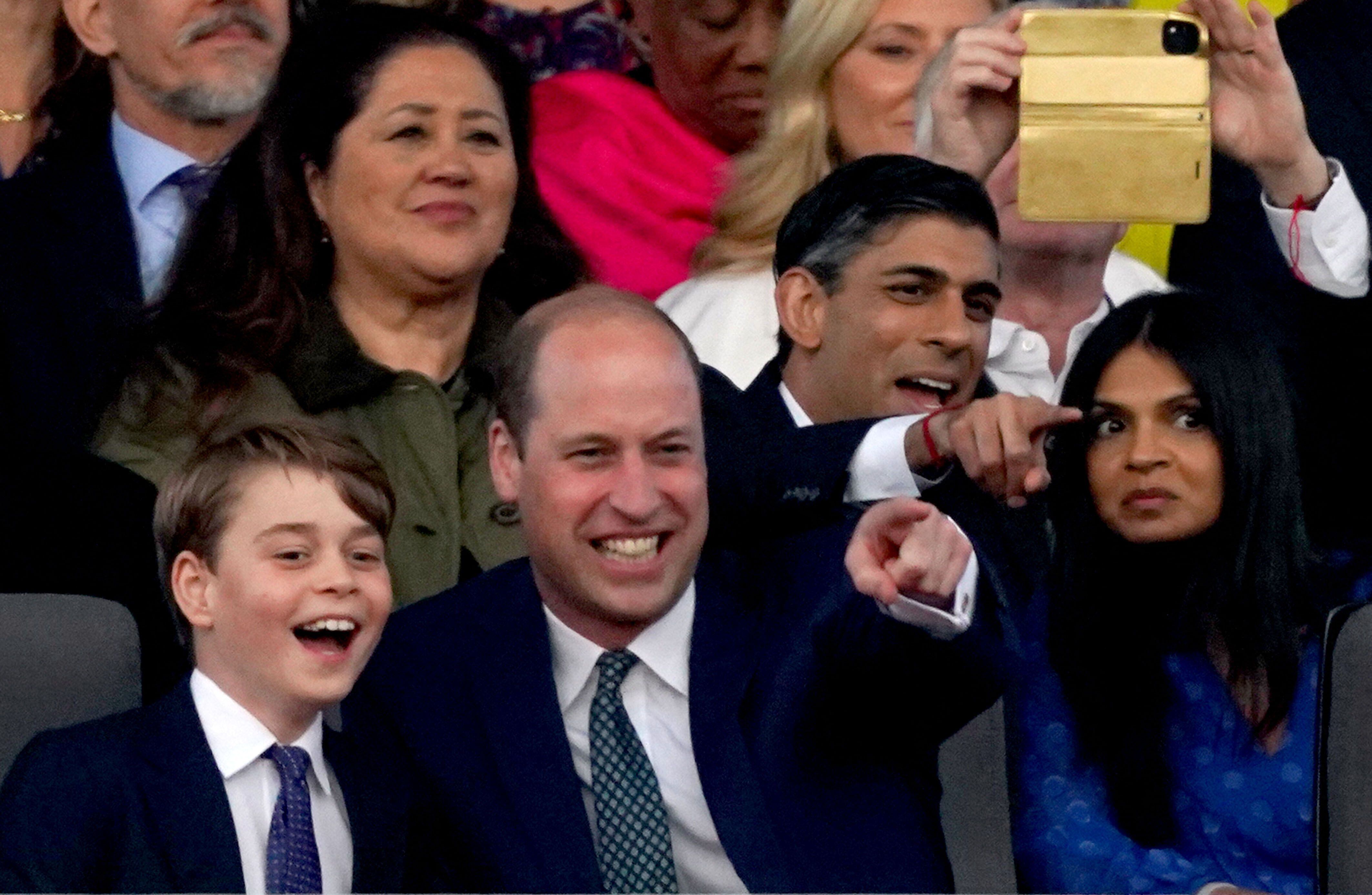 El príncipe Guillermo y su hijo mayor, sentados delante del primer ministro británico, Rishi Sunak, y su esposa, Akshata Murty, ven el concierto en el castillo de Windsor con motivo de la coronación de Carlos III de Inglaterra, este domingo. 