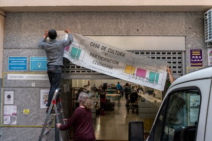 Tres activistas cuelgan el cartel de la Casa de la Cultura de Chamberí.