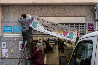 Tres activistas cuelgan el cartel de la Casa de la Cultura de Chamberí.