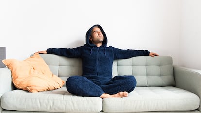 Un hombre con pijama de forro polar en el sofá de su casa.