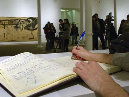 Una persona firma en el libro de condolencia situado en la fundaci&oacute;n T&agrave;pies de Barcelona.