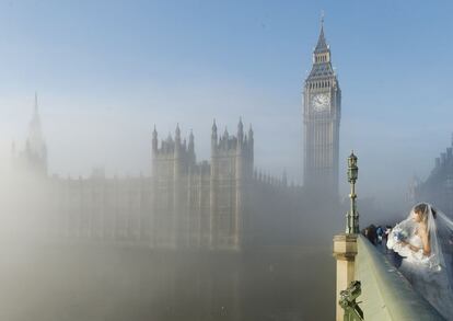 Londres (Reino Unido), 11 de diciembre de 2013. Una novia posa para un fotógrafo en el puente de Westminster, frente al parlamenteo británico y el archiconocido 'Big Ben'.