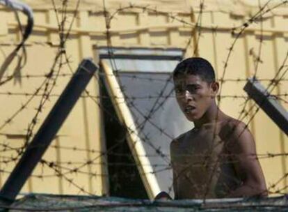 Un inmigrante mira a través de la alambrada de un centro de acogida en Lampedusa en junio de 2003.