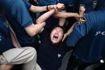 Una joven manifestante es detenida por agentes de policía que ha intentado entrar en la embajada japonesa en Seúl en una protesta contra el vertido del agua contaminada de Fukushima.