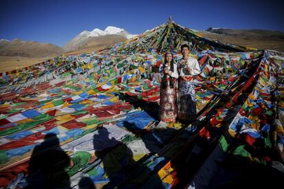 Jing Li y su marido, Ke Xu vestidos con los trajes tradicionales posan para sus fotos de boda delante de banderas de oración tibetanas en el paso de montaña Nianqing Tanggula en la Región Autónoma del Tíbet. Ke , de 23 años, y Jing , de 22 años , ambos de Shiyan , en el noroeste de Hubei provincia viven en el Tíbet durante tres años. La pareja se casó el mes pasado .