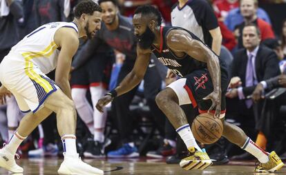 Klay Thompson trata de frenar a Harden.  