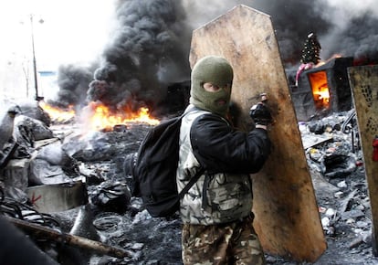 Un manifestante se protege detrás de un escudo improvisado durante los enfrentamientos con la policía en el centro de Kiev (Ucrania), 23 de enero de 2014. 