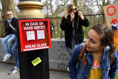 Una joven observa un cartel en el que se ve una caja de emergencia que contiene dos bolsas de té, durante la marcha de Londres.