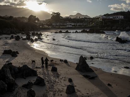 Dos mujeres con sus perros en la playa de Toró, Llanes, el 21 de enero.