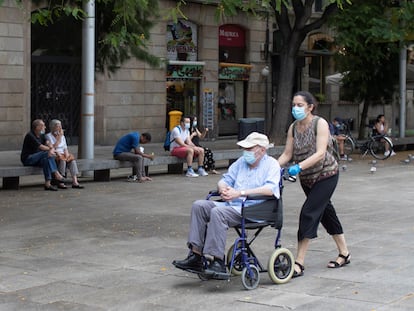 Una mujer pasea a un señor en silla de ruedas, el año pasado en el centro de Barcelona.