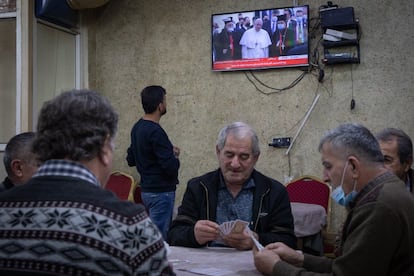 Un grupo de hombres juega a las cartas, en una casa de té de Erbil (Irak), mientras se retransmite por televisión la llegada del Papa. El Pontífice, el primero que visita el país, busca acercarse a las minorías cristianas de Irak y, al mismo tiempo, tender puentes con el islam chií a través de uno de sus principales líderes: el gran ayatolá Ali Sistani.