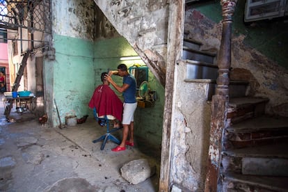 Un barbero realiza un corte bajo las escaleras de su edificio de departamentos en La Havana, Cuba, en una fotografía de archivo.