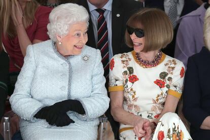 Reina Isabel II y Anna Wintour en la Semana de la Moda de Londres
Hace un año, la Semana de la Moda de Londres tuvo la que probablemente sea la visita más ilustre que haya recibido en toda su historia. La reina de Inglaterra tomó sitio en el front row del desfile de Richard Quinn junto a la directora del Vogue estadounidense, otra soberana, aunque de corte plebeyo, con la que compuso una de las estampas más insólitas de la temporada. Para lograr el peinado de la monarca, nada mejor que recurrir a la tradicional técnica de los rulos, “aunque primero hay que preparar el cabello con una hidratación ligera y aplicar un voluminizador para, al cepillarlo, conseguir un efecto de esponjosidad”, añade Gema. Para el vestuario, la clave es “un traje de tweed azul clarito, pendientes de perla redonda y un broche de brillantes en la solapa". Y para cerrar el estilismo “unos guantes largos negros, unas medias blancas cristal y unas merceditas de charol negro”. Para la cara, David opta por “piel empolvada, colorete aplicado en la zona alta del pómulo y sombra de ojos en tonos claros, y una ceja difuminada, casi imperceptible".
Anna Wintour se presta mucho al disfraz. Para Cristina, el peinado y sus icónicas gafas negras bastan para lograr un look inequívoco, que complementaría con “un vestido midi con estampado pañuelo y unas botas de caña alta”. El peinado requiere “un blushing minucioso, mejor con un cepillo nanotérmico para aportar soltura y movimiento, y trabajarlo sin restarle humedad”. Para el rostro, eternamente oculto tras los cristales oscu, bastaría con “labios en un tono natural y con ausencia de brillo”.