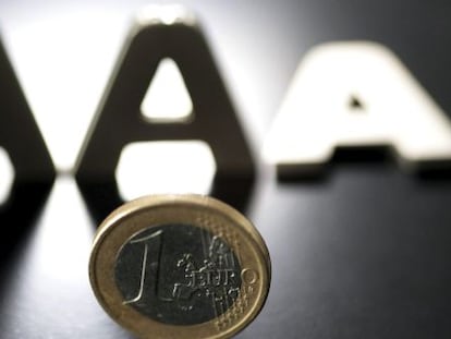 En la imagen, una moneda de euro junto a tres letras &quot;A&quot;, una de las cuales aparece tumbada. 