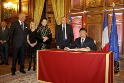 El ministro de Exteriores francés, Laurent Fabius (i), y el alcalde de Lyon, Gerard Collomb (2-d), observan cómo el presidente de China, Xi Jinping (d), firma en el libro de visitas a su llegada ayer a una cena en el Ayuntamiento de Lyon (Francia).