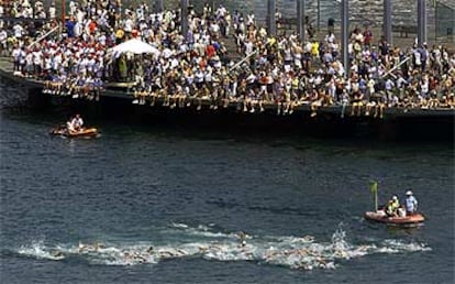Decenas de espectadores siguen la prueba de cinco kilómetros en aguas abiertas.