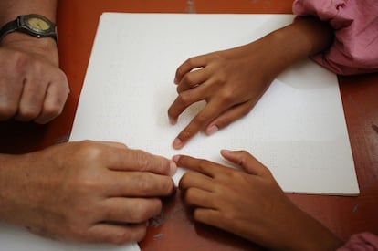 Un profesor guía el dedo de su alumna sobre un ejemplar en braille del Corán.