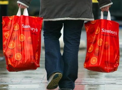 Un cliente de un supermercado de Reino Unido, cargado con dos bolsas de plástico.