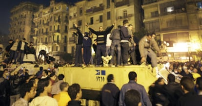 Decenas de manifestantes rodean y se suben a vehículos blindados del Ejército cerca de la plaza Tahrir, epicentro de las protestas en El Cairo.