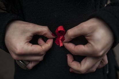 Una mujer se coloca una cinta roja, símbolo de la lucha contra el sida durante una manifestación en el día mundial del sida, en Pamplona.