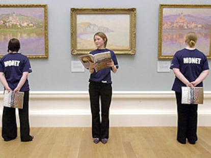 Tres guías con camisetas y catálogos de la exposición de Monet, ante tres cuadros del pintor en la Real Academia Escocesa.