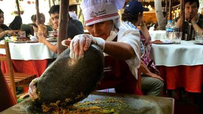 Cozinheira esmaga alimentos num ‘batán’ no restaurante La Nueva Palomino, em Arequipa.