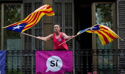 Una mujer muestra una dos esteladas desde un balcón en Barcelona.