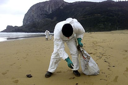Un operario recoge chapapote en la playa vizcaína de Laga.