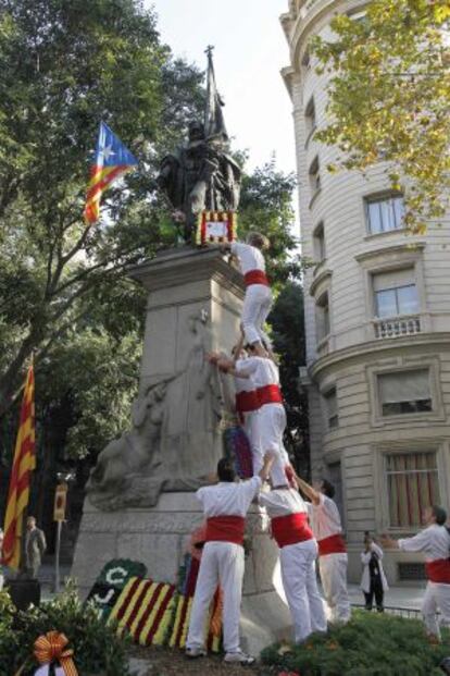 El grupo casteller Falcons de Barcelona coloca un ramo en el monumento de Rafael Casanova, que porta una bandera independentista.
