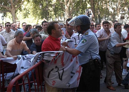 Un agente se enfrenta a un taxista durante las protestas de ayer en el Ayuntamiento de Sevilla.

Ventana rota durante las protestas de ayer.