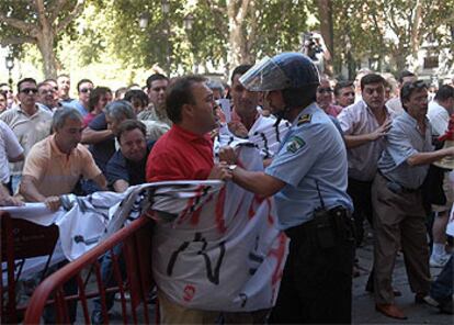 Un agente se enfrenta a un taxista durante las protestas de ayer en el Ayuntamiento de Sevilla.
Ventana rota durante las protestas de ayer.