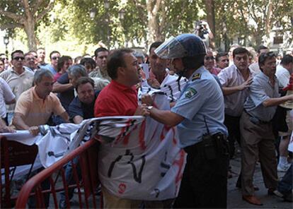 Un agente se enfrenta a un taxista durante las protestas de ayer en el Ayuntamiento de Sevilla.

Ventana rota durante las protestas de ayer.