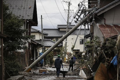 Los residentes caminan por la carretera cubierta de lodo en un vecindario devastado por el tifón Hagibis en Nagano (Japón).