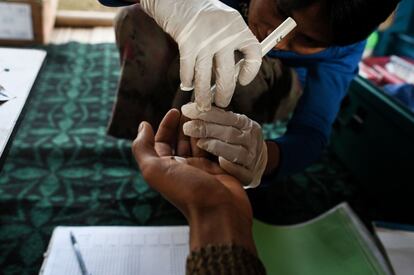 Htan Pi, un trabajador de salud comunitario, realiza la prueba de la malaria a un paciente en su casa de la aldea de Satpalaw Shaung.