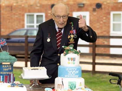 A handout picture released on April 30, 2020 shows Captain Tom Moore posing for a photograph with cakes to celebrate his 100th birthday in Marston Moretaine, north of London. (Photo by Emma SOHL / CAPTURE THE LIGHT / AFP) / RESTRICTED TO EDITORIAL USE - MANDATORY CREDIT "AFP PHOTO / CAPTURE THE LIGHT / EMMA SOHL" - NO MARKETING NO ADVERTISING CAMPAIGNS - DISTRIBUTED AS A SERVICE TO CLIENTS --- NO ARCHIVE ---