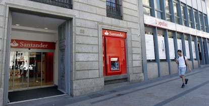 Un viandante pasa ante dos oficinas contiguas de Santander y Popular, este mi&eacute;rcoles en Madrid.