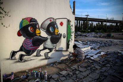 Mue Bon, artista callejero tailandés, pinta un mural que representa la lucha contra el coronavirus.