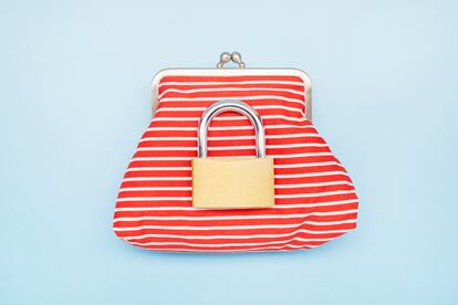 High angle view of a wallet and closed padlock on blue background