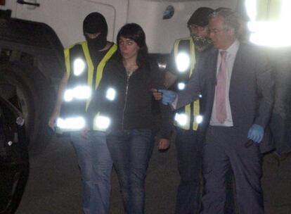 Dos agentes conducen a una detenida en presencia del juez de la Audiencia Nacional Baltasar Garzón.