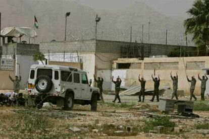 Prisioneros palestinos salen de la cárcel con las manos en alto ante la mirada de un grupo de mujeres palestinas.