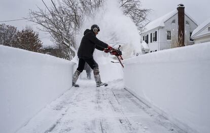 El aeropuerto de Binghamton reportó casi un metro de nieve, según el Servicio Meteorológico Nacional. En la imagen, una mujer limpia la acera en Binghamton, Nueva York.