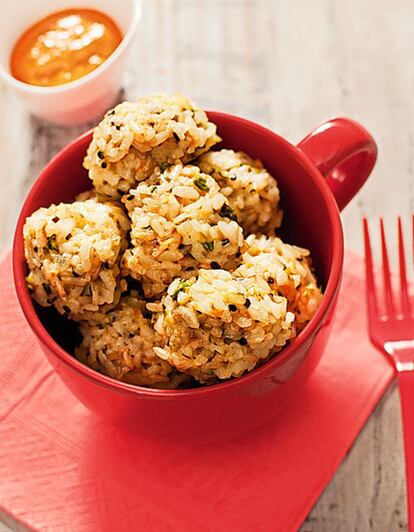 <p><i>Ingredientes</i></p><p> Para 4 personas: Para las albóndigas, 150 gramos de arroz redondo, 1 taza de zanahoria rallada, 1 taza de calabacín rallado, 1 cebolla, 2 huevos, 100 gramos de queso tipo gouda rallado, 1 cucharada sopera rasa de semillas de ajenuz, 1 cucharadita de hojas de tomillo fresco, sal, pimienta. Para el romesco, 2 tomates, 2 ñoras (o 1 cucharada de carne de pimiento choricero), 1 cabeza de ajos, 5 gramos de almendras tostadas peladas, 1 rebanada de pan tostado, 60 mililitros de vinagre de vino blanco, 100 mililitros de aceite de oliva virgen extra, 1 cucharadita de pimentón rojo dulce, sal al gusto. </p><p><i> Preparación</i></p><p> 1. El día antes, poner la ñora en remojo para poder sacarle toda la carne y semillas. Escalivar en el horno a 200 grados durante unos 20 minutos los tomates –tienen que perder parte de su jugo– y durante unos 30-35 la cabeza de ajos. 2. Dejar enfriar y eliminar pieles y pepitas para procesar junto al resto de los ingredientes hasta conseguir una pasta tan fina como se quiera. Reservar en la nevera. 3. En una sartén con dos cucharadas de aceite sofreír la zanahoria y el calabacín rallados con la cebolla pelada y picada durante 10 minutos. 4. Hervir el arroz en abundante agua salada hasta que esté bien hecho. Escurrir y mezclar –todavía caliente– con el queso rallado, el ajenuz, el tomillo, sal, pimienta y los huevos batidos. 5. Hacer bolitas con la masa, meter al horno a 200 grados, en una bandeja con papel especial, durante unos 15 minutos o hasta que las bolitas estén compactas y ligeramente doradas.</p>