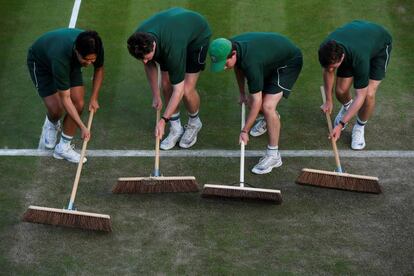 Personal de tierra barren una de las pistas de tenis de Wimbledon, el 4 de julio de 2017.