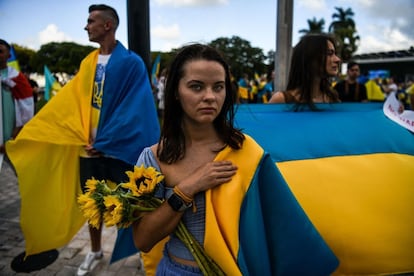 Una joven sostiene girasoles, la flor nacional de Ucrania, mientras protesta contra la invasión rusa y pide una zona de exclusión aérea, durante un mitin en Miami, Florida (EE UU).