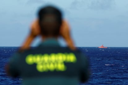 Un guardia civil observa a un barco de rescate que busca los cuerpos de víctimas del naufragio de un cayuco junto a la costa de El Hierro, este sábado.