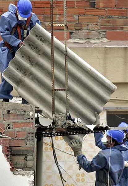 Trabajadores con protección manipulando amianto.