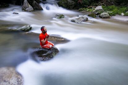 Un peregrino hindú, también conocido como Bolbom, reza mientras recoge agua del río Bagmati para entregarla en el templo Pashupati como adoración a Shiva, dios de la creación y de la destrucción, en Sundarijal, Katmandú (Nepal).