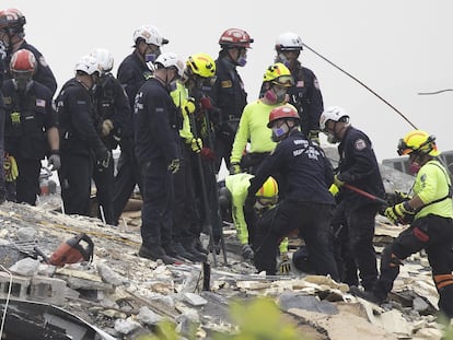 Miembros de la unidad de rescate de Florida buscan desaparecidos entre los escombros.