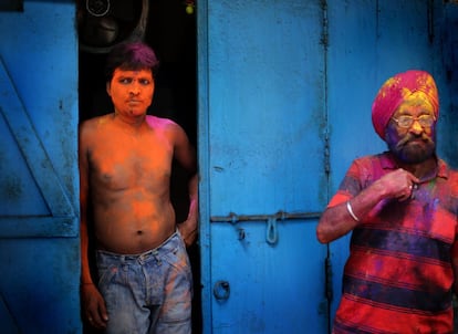 Dos hombres impregnados de polvos de colores observan al resto de personas que participaron en la celebración del festival Holi en Kolkata (India), el 1 de marzo de 2018.