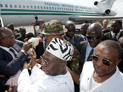 El presidente de Liberia, Taylor (derecha), y su homólogo nigeriano, Obasanjo (centro), en el aeropuerto de Monrovia.
